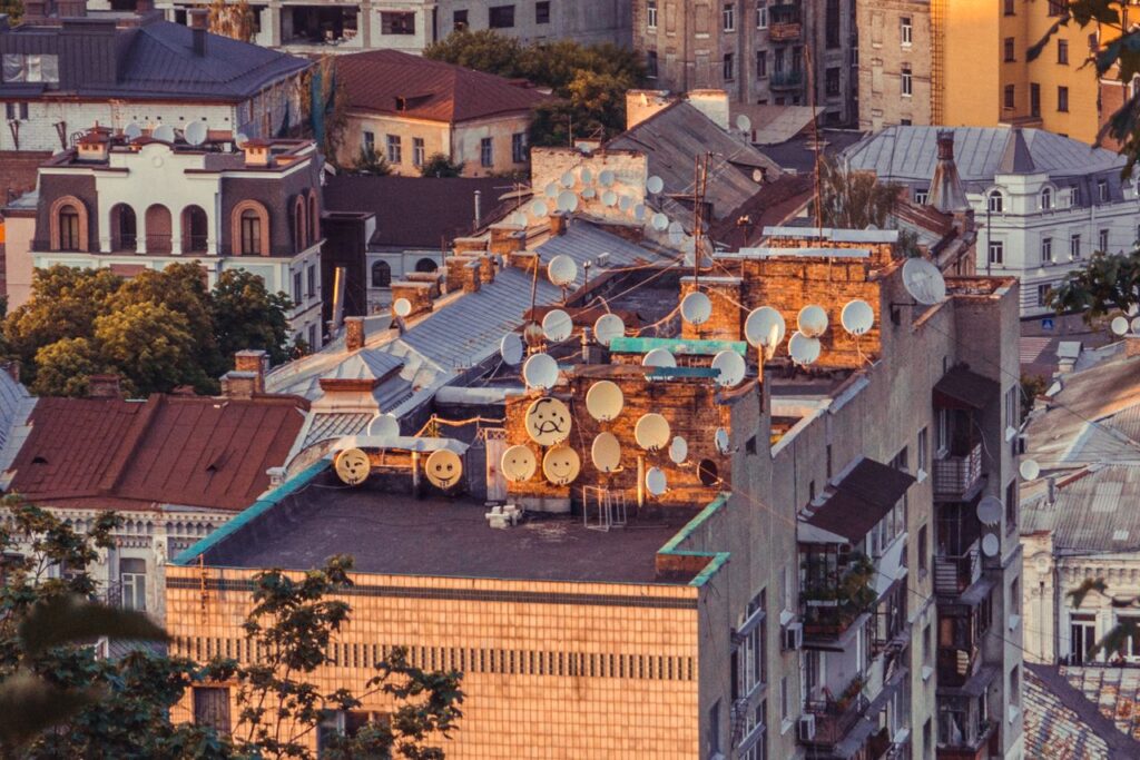 Aerial view of numerous satellite dishes on a rooftop in Kyiv, Ukraine during sunset.